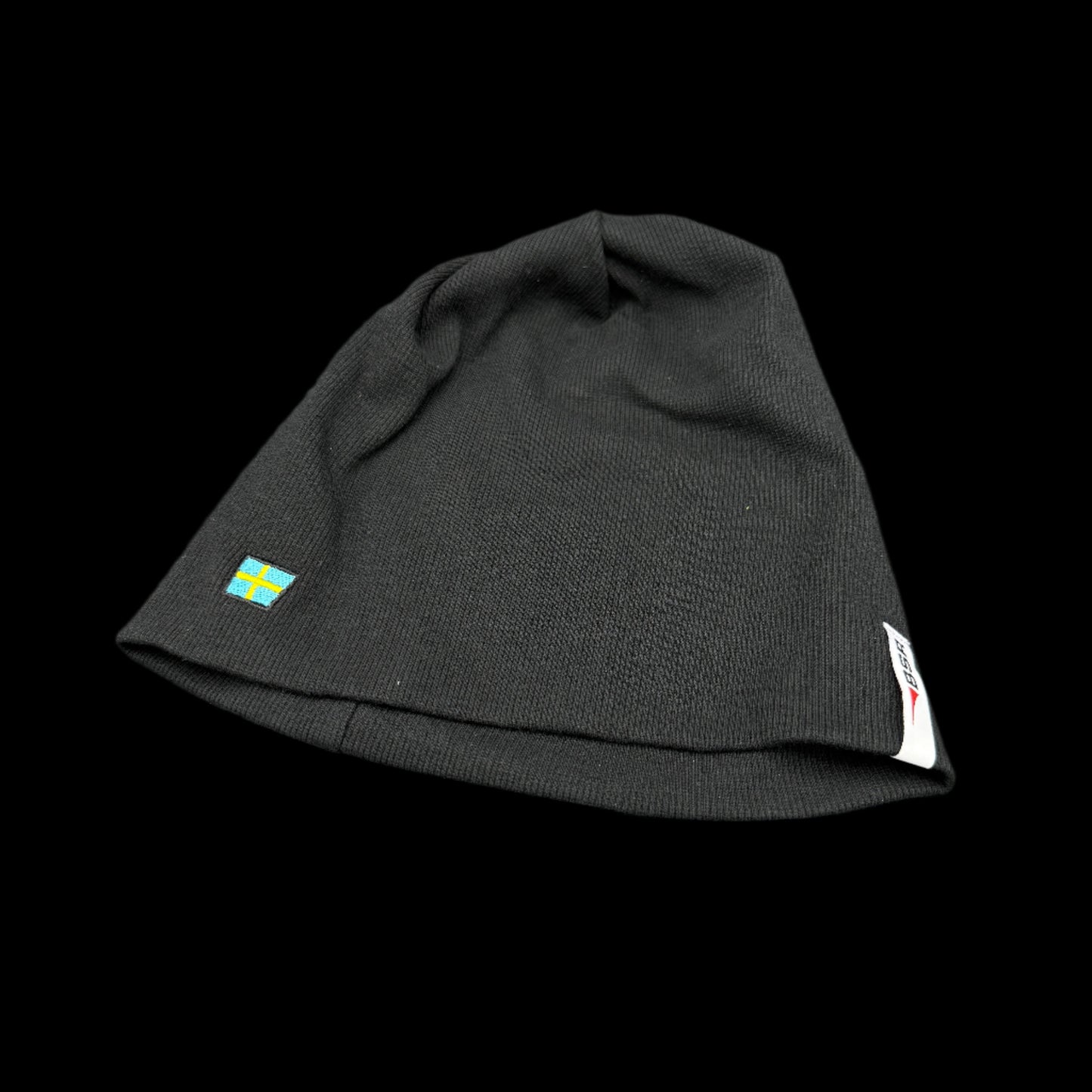 Black beanie with a small flag emblem on a gray background
