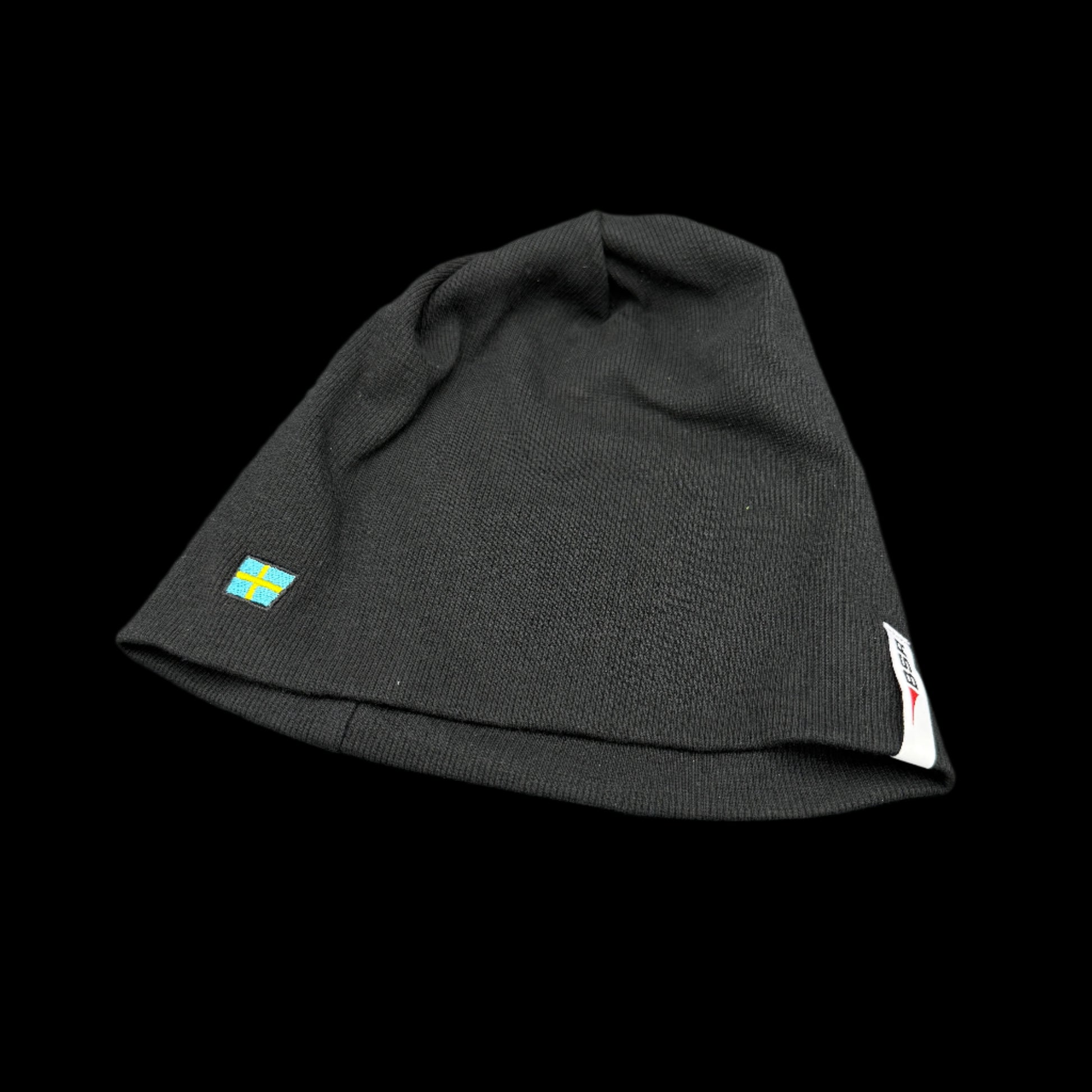 Black beanie with a small flag emblem on a gray background